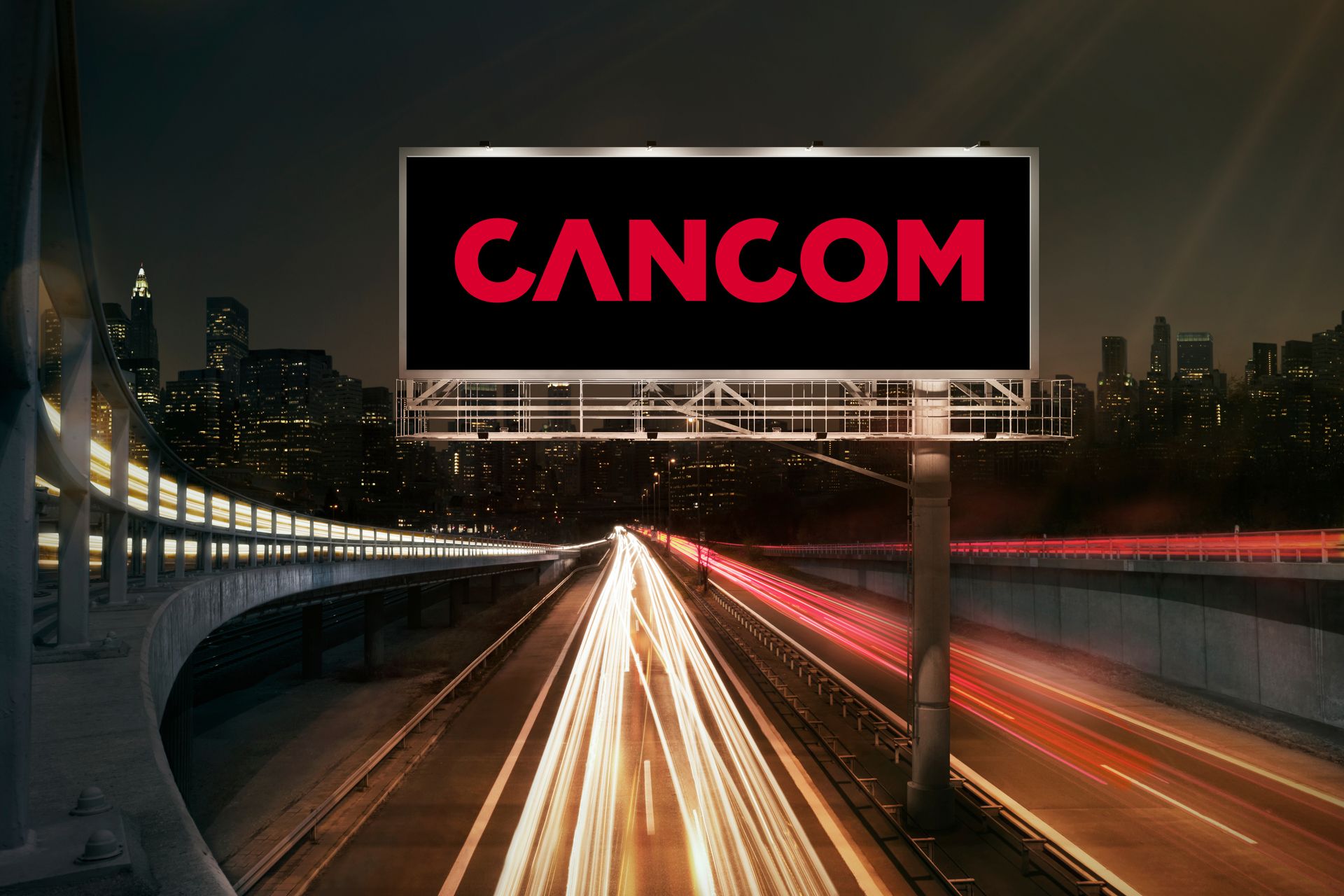 An illuminated billboard in front of a nocturnal cityscape promoting CANCOM digital signage solutions.