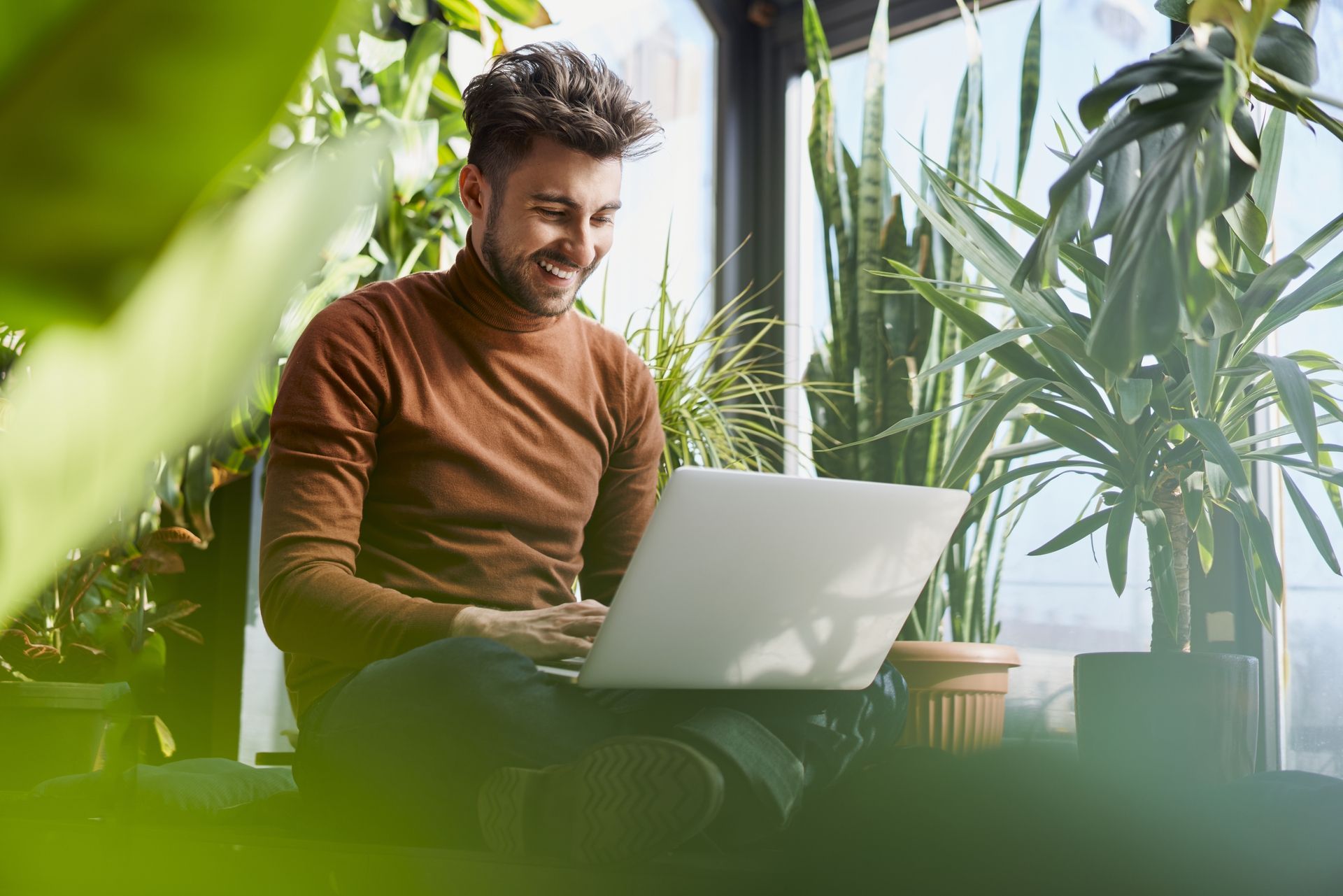Man sits on the floor with a laptop and works on sustainable digitalization solutions.