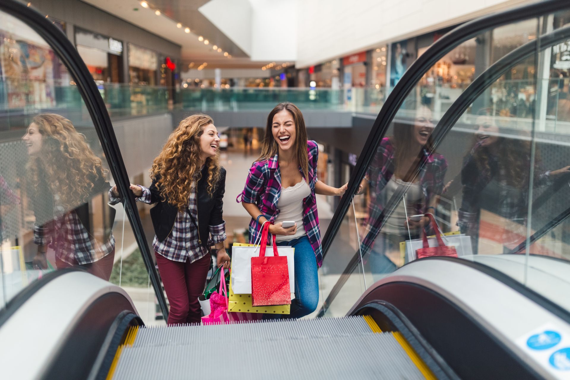 Two women on an escalator in a building.