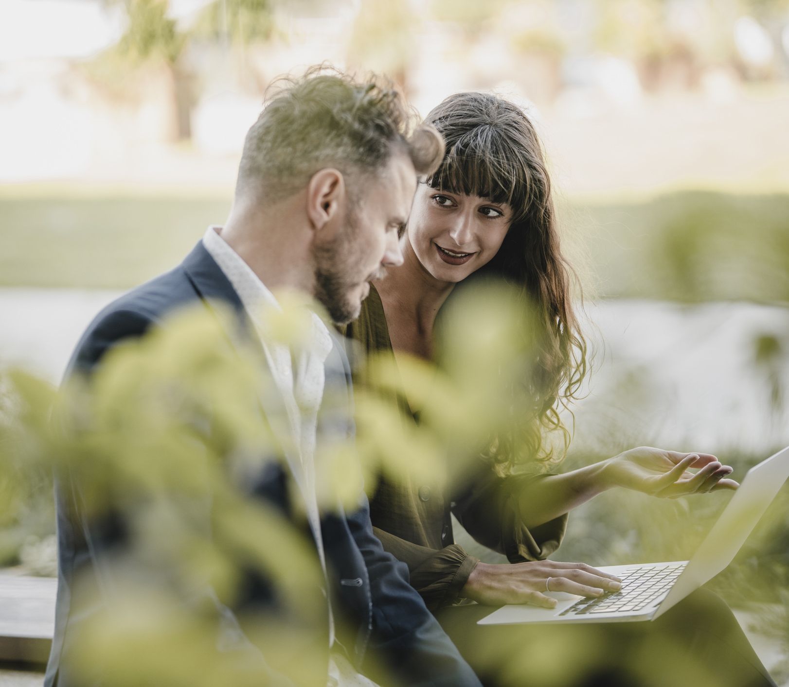 Man and woman sitting outside looking at a laptop to discuss energy management solutions.